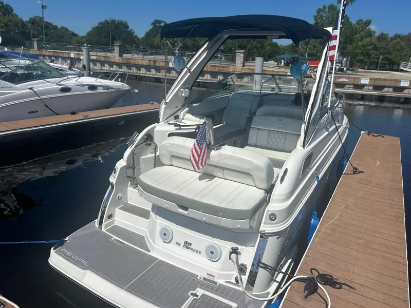 Slide: The Image of 2022 Regal 28 Express boat docked, featuring a spacious seating area and American flag. - 4