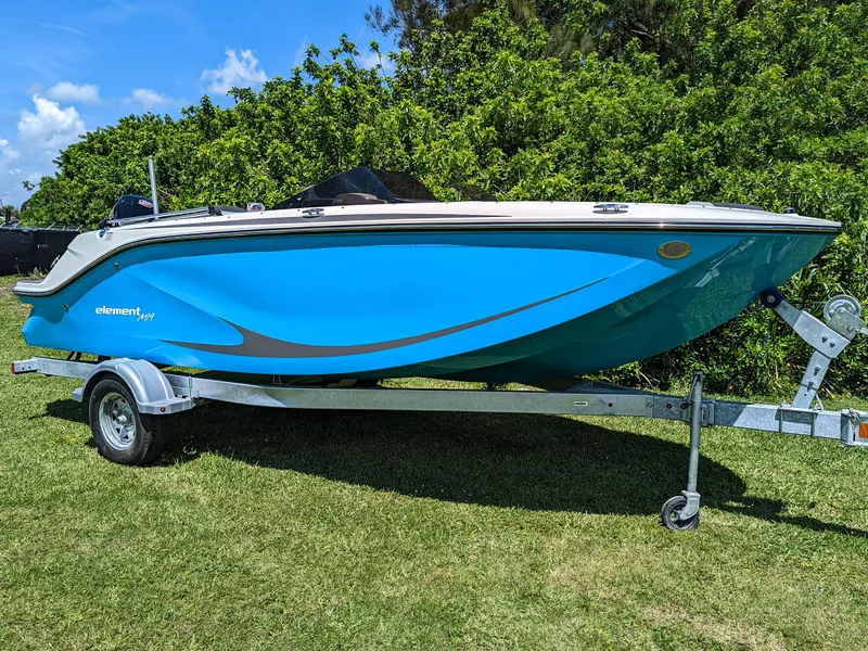 Slide: The Image of 2024 Bayliner Element M19 boat on trailer, vibrant blue hull, parked on grass. - 11
