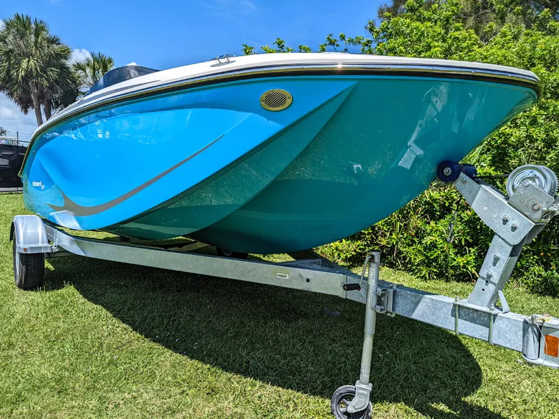 Slide: The Image of 2024 Bayliner Element M19 boat on trailer, vibrant blue hull, parked on grass. - 12