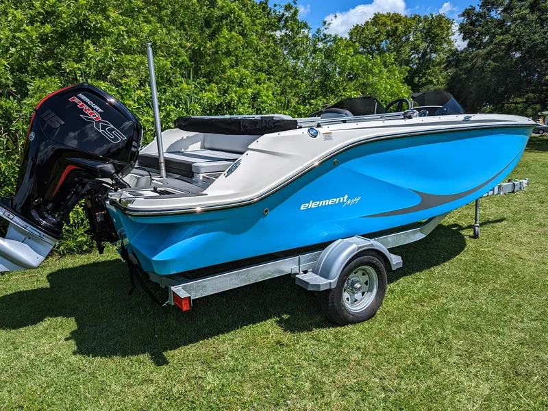 Slide: The Image of 2024 Bayliner Element M19 boat on trailer, vibrant blue, parked on grass. - 13