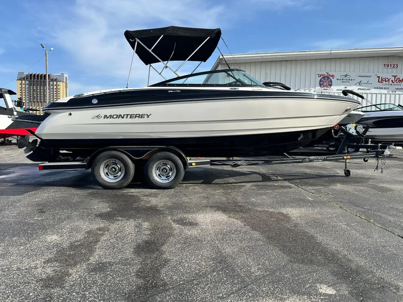 Slide: The Image of 2013 Monterey 224FXS boat on trailer, black and white design, parked outdoors. - 1