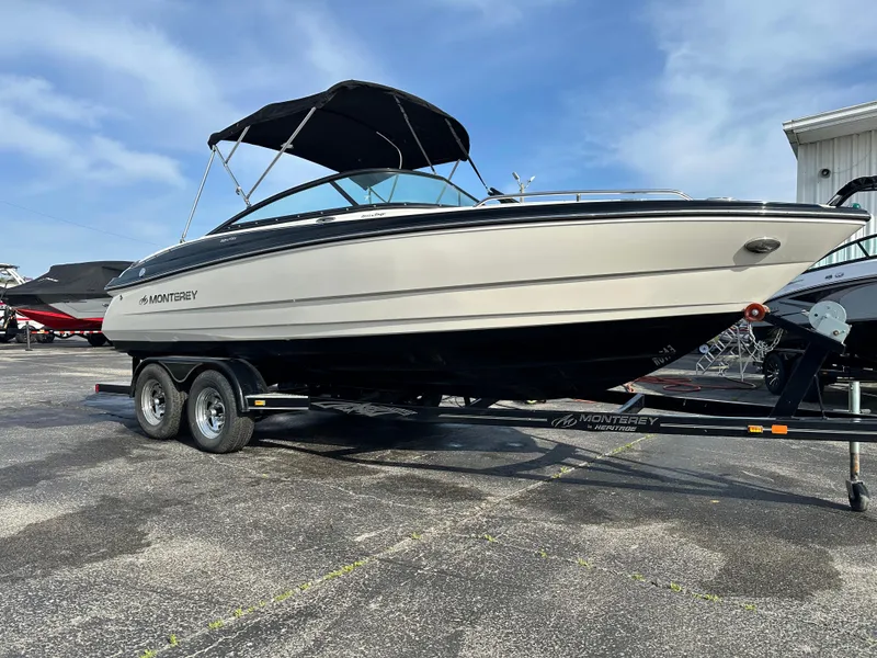Slide: The Image of 2013 Monterey 224FXS boat on trailer, parked outdoors under a clear sky. - 2