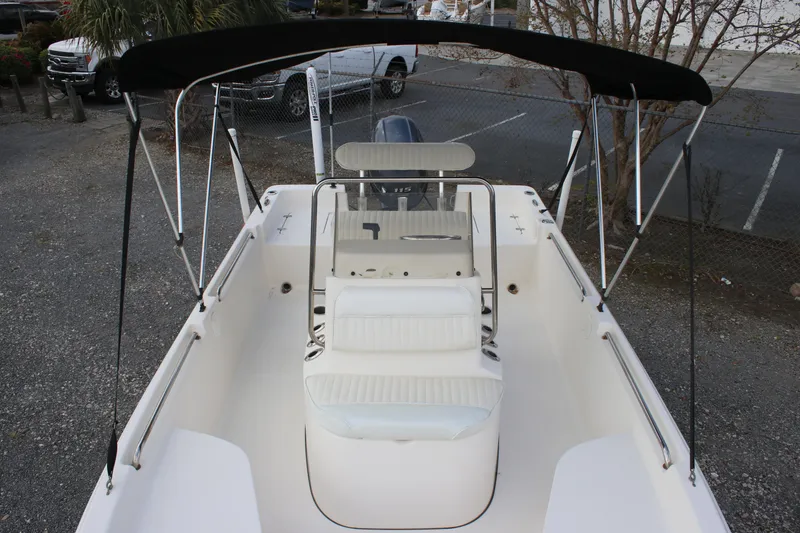 Slide: The Image of 2015 Bulls Bay 2000 boat with canopy, white seating, and steering console, parked outdoors. - 4