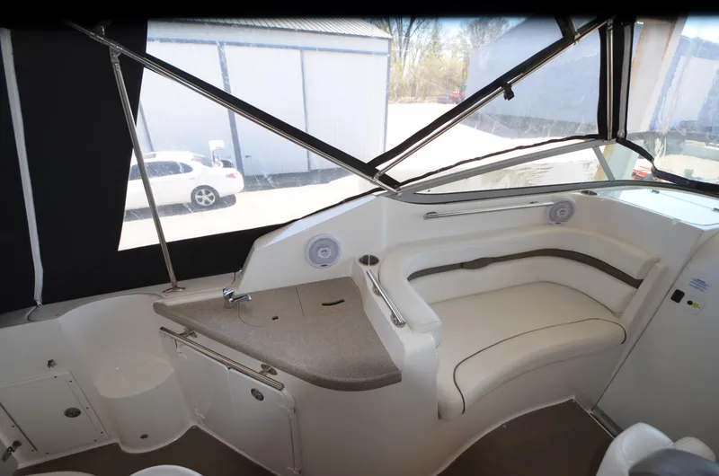 Slide: The Image of 2008 Rinker 260 EC boat interior with seating and counter, docked near a building. - 16