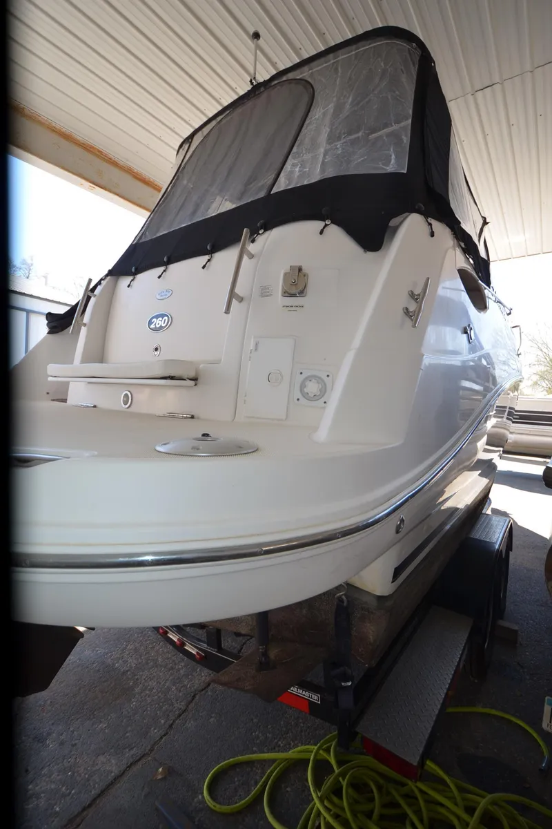 Slide: The Image of 2008 Rinker 260 EC boat with black canopy, docked indoors. - 21