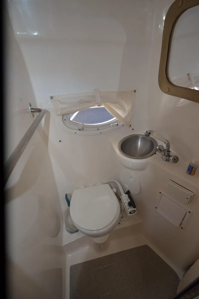 Slide: The Image of Compact bathroom in 2008 Rinker 260 EC boat with toilet, sink, and porthole. - 23