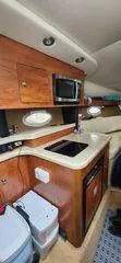 Slide: The Image of 2008 Rinker 260 EC boat interior with kitchenette, microwave, and wooden cabinetry. - 7