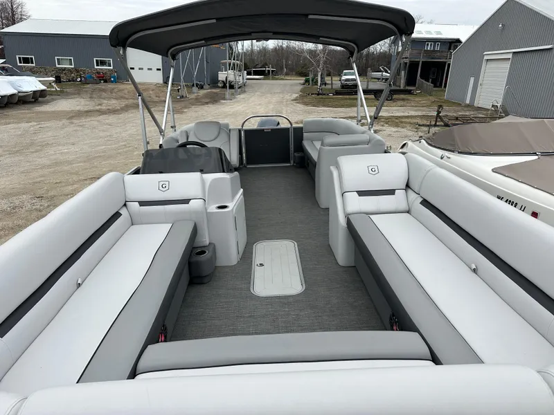 Slide: The Image of 2021 Godfrey Sweetwater 2486 SB pontoon boat with spacious seating and canopy in a yard. - 16