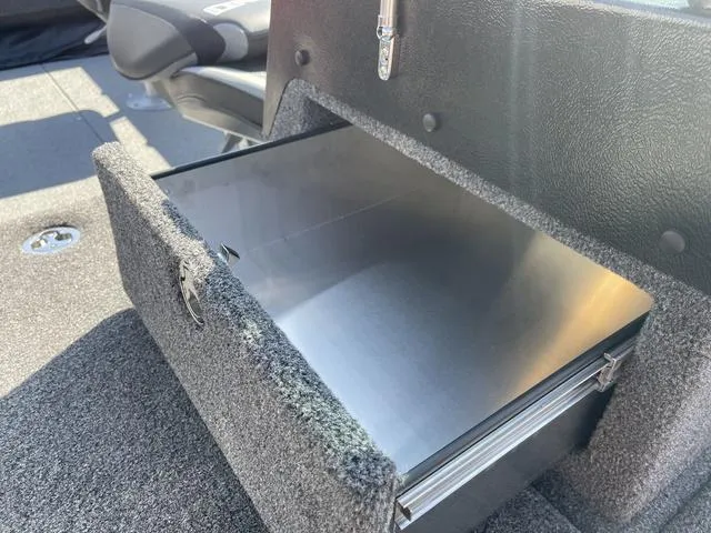 Slide: The Image of Open storage compartment in 2025 Lund 2075 Pro-V Sport boat, featuring a sleek metal interior. - 13