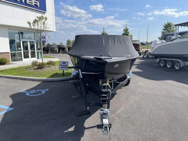Slide: The Image of 2025 Lund 2075 Pro-V Sport boat with cover, parked outside dealership on sunny day. - 2