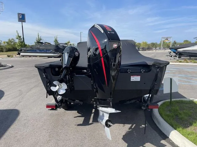 Slide: The Image of 2025 Lund 2075 Pro-V Sport boat with dual outboard motors in a parking lot. - 5