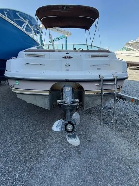 Slide: The Image of 1999 Chaparral 2135 SS boat, rear view with propeller and ladder, parked on gravel. - 7