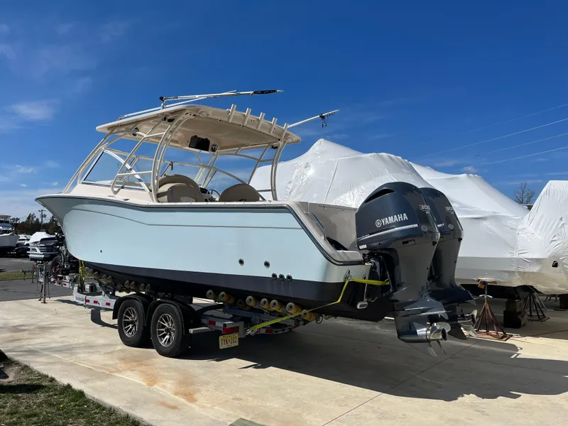 Slide: The Image of 2013 Grady-White Freedom 307 boat on trailer with Yamaha engines, parked outdoors. - 1