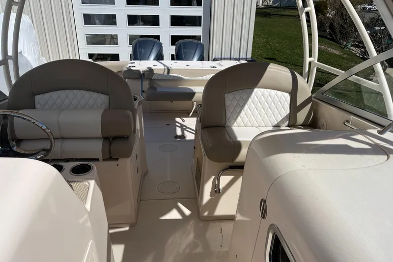 Slide: The Image of 2013 Grady-White Freedom 307 boat interior with cushioned seating and dual engines. - 14