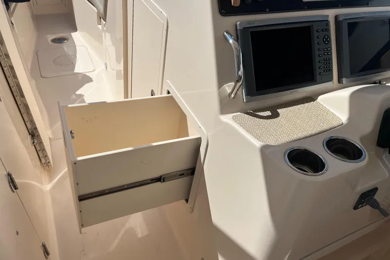 Slide: The Image of 2013 Grady-White Freedom 307 boat interior with open storage drawer and control panel. - 25