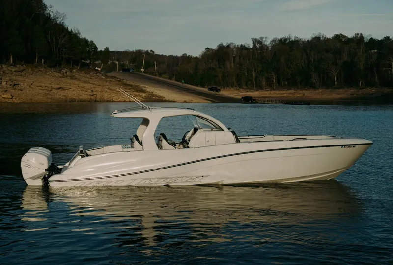 Slide: The Image of 2021 Deep Impact 399 Sport boat on calm lake with wooded shoreline. - 2