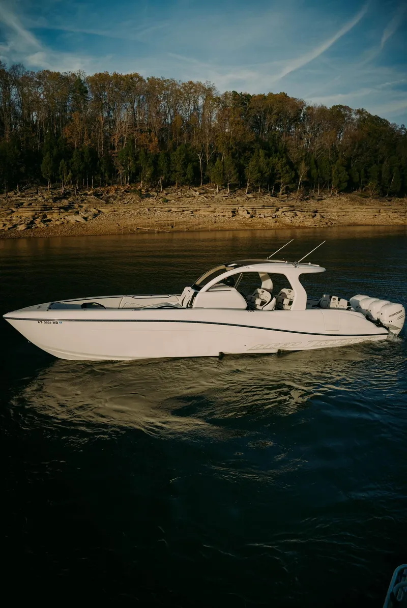 Slide: The Image of 2021 Deep Impact 399 Sport boat cruising on a calm lake near a wooded shoreline. - 23
