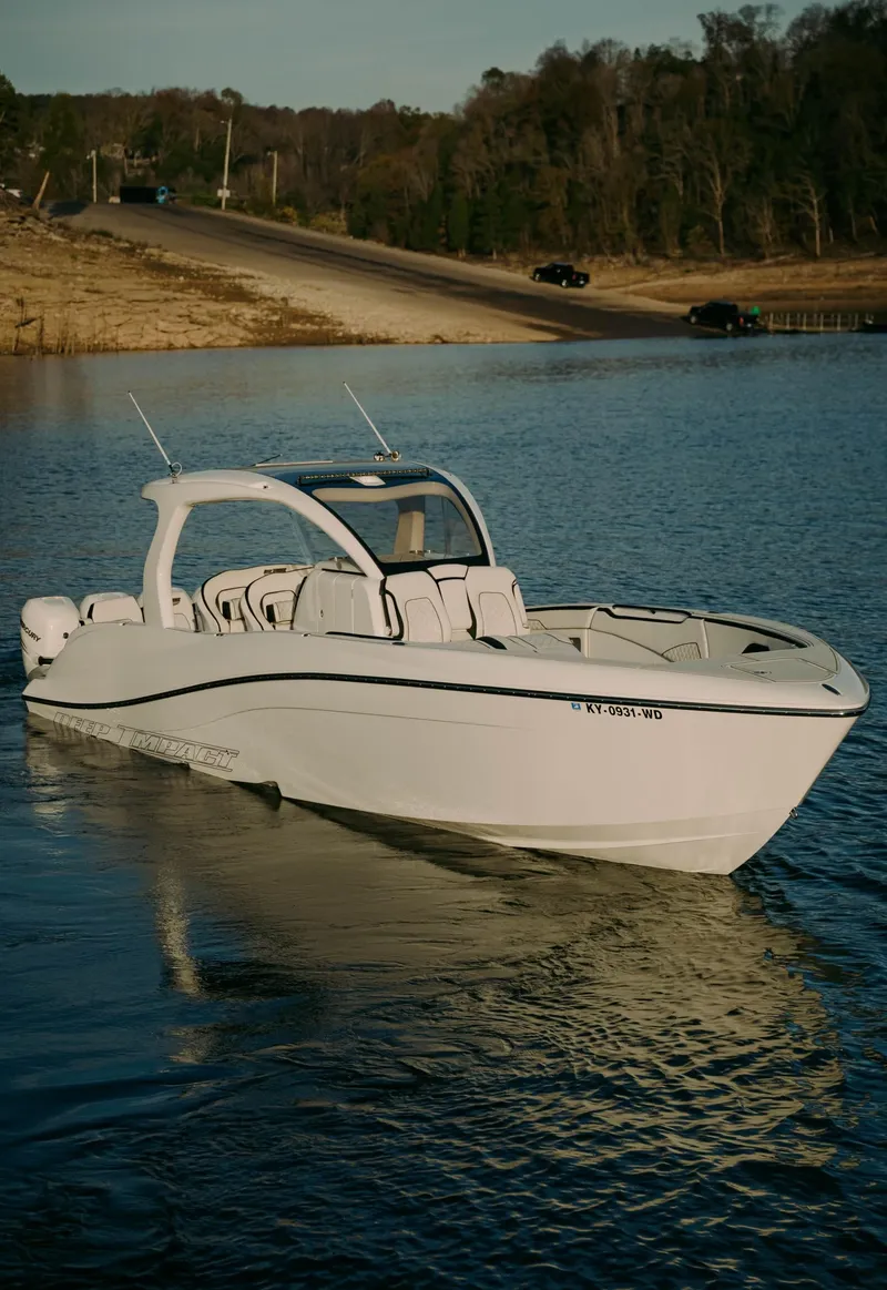 Slide: The Image of 2021 Deep Impact 399 Sport boat on calm water near a shoreline. - 24