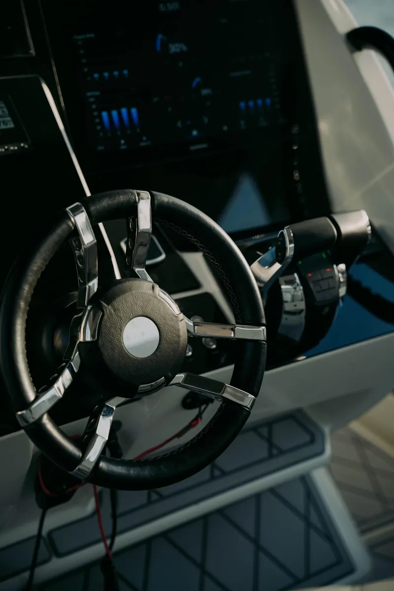 Slide: The Image of Steering wheel of a 2021 Deep Impact 399 Sport boat, featuring modern controls and dashboard. - 9