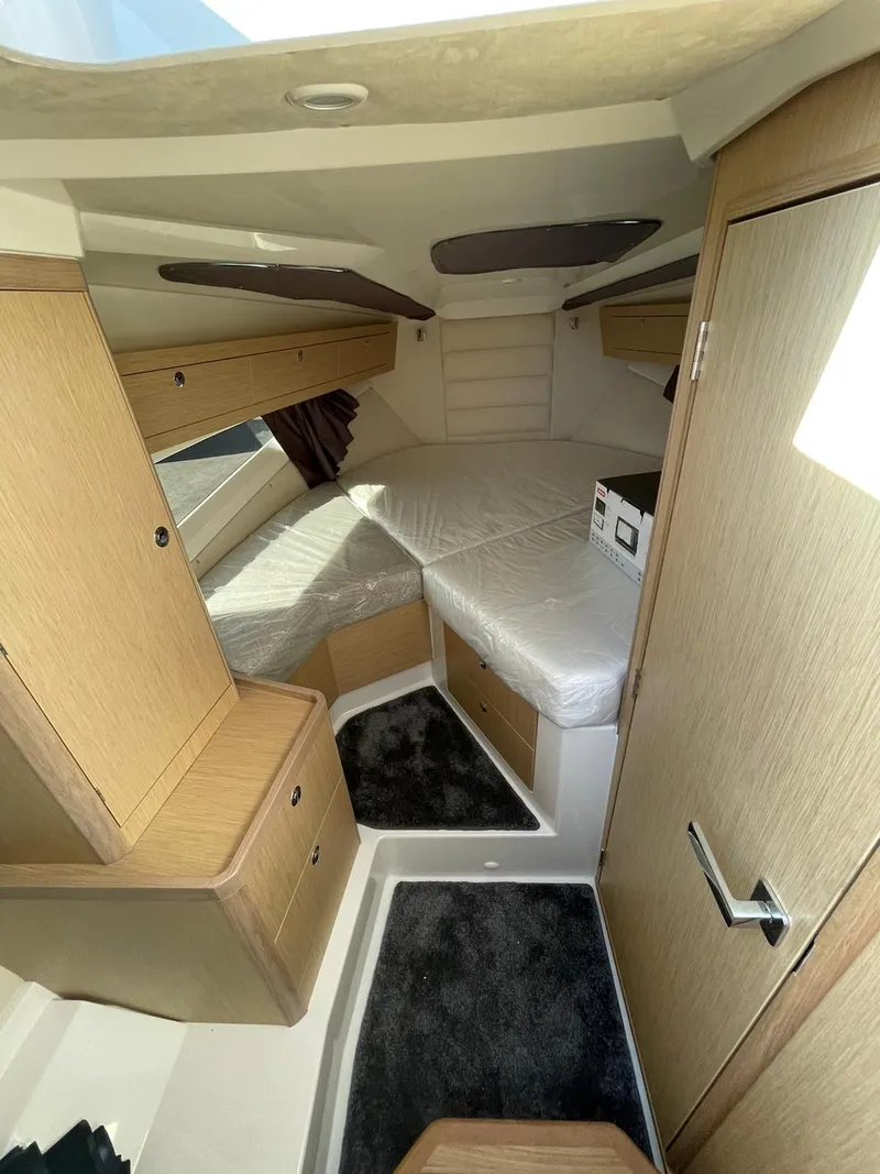 Slide: The Image of Interior of 2022 Parker Poland 850 Voyager boat, featuring cozy cabin with bed and storage. - 6