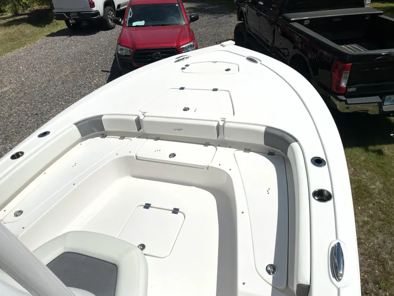 Slide: The Image of 2020 Tidewater 2300 Carolina Bay boat, white interior, parked near trucks. - 24