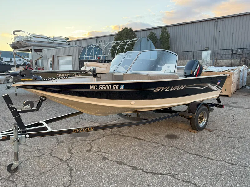 Slide: The Image of 2004 Sylvan 1600 Explorer DC boat on trailer, parked outdoors near industrial building. - 2