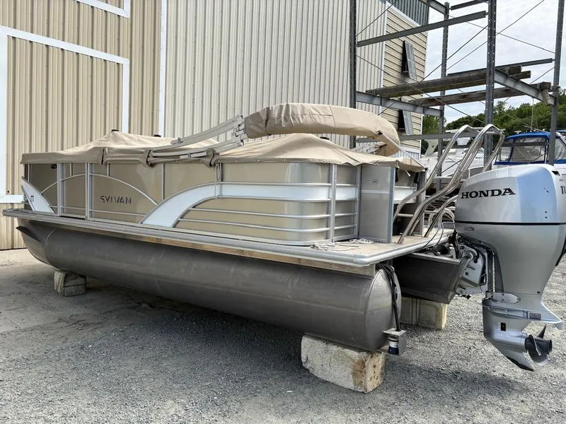 Slide: The Image of 2019 Sylvan 8520 Mirage F-n-C pontoon boat with Honda outboard motor, stored on blocks. - 2