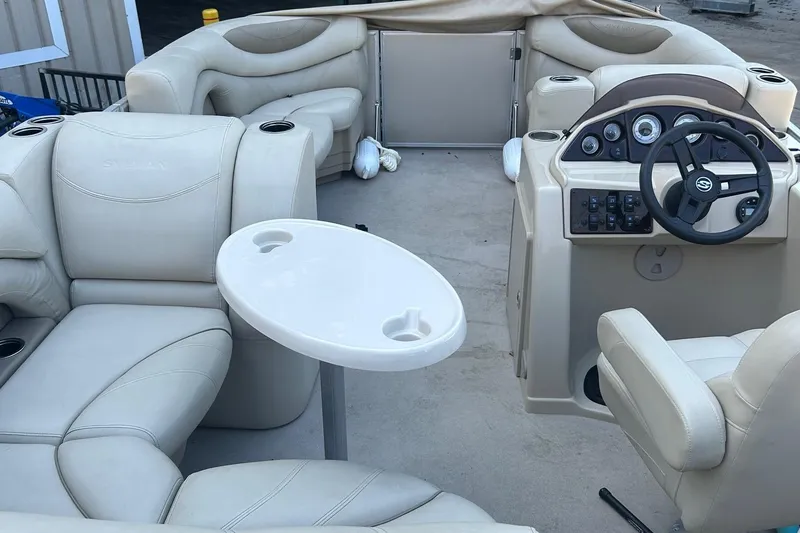 Slide: The Image of 2019 Sylvan 8520 Mirage F-n-C boat interior with beige seating and steering console. - 7