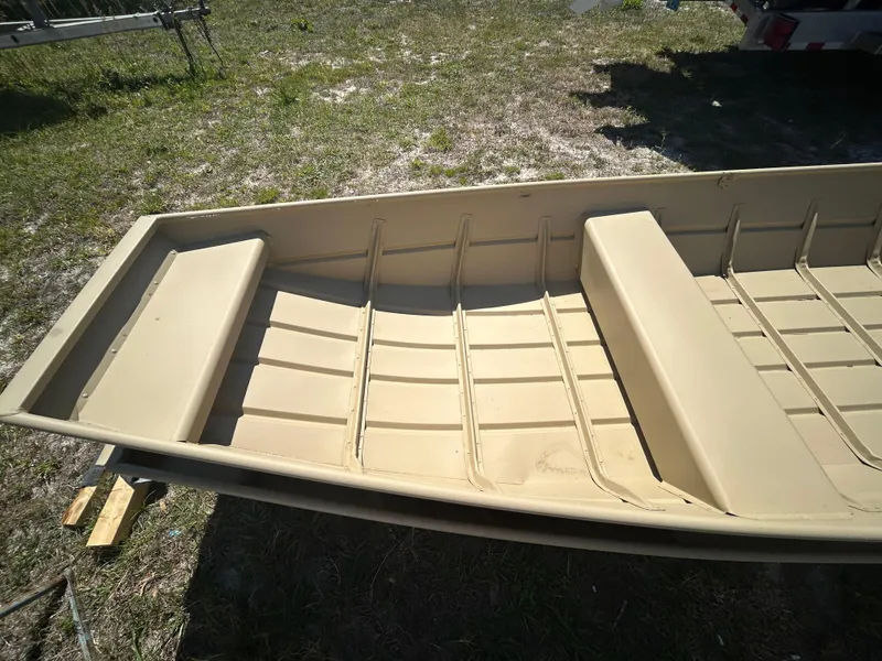 Slide: The Image of 2025 Crestliner CR1436L boat interior, beige color, on grassy ground. - 4