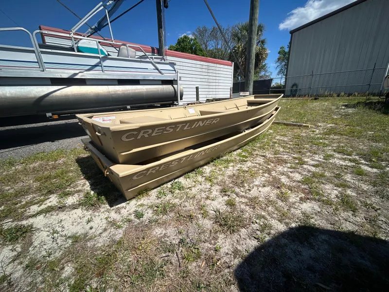 Slide: The Image of 2025 Crestliner CR1436L boats stacked outdoors on grass, under clear blue sky. - 8