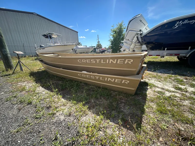 Slide: The Image of 2025 Crestliner CR1436L boats on grass near a warehouse, under a clear blue sky. - 9
