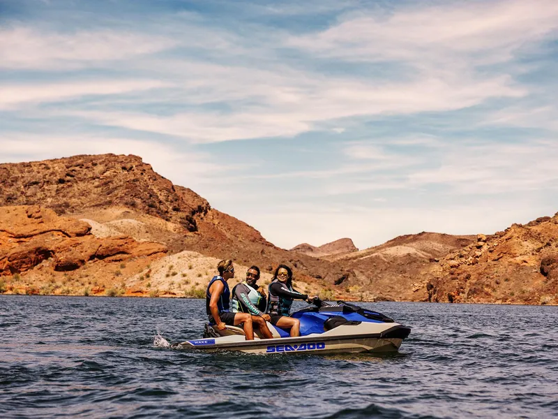 Slide: The Image of 2025 Sea-Doo Wake Pro 230 with three riders on a scenic lake. - 19