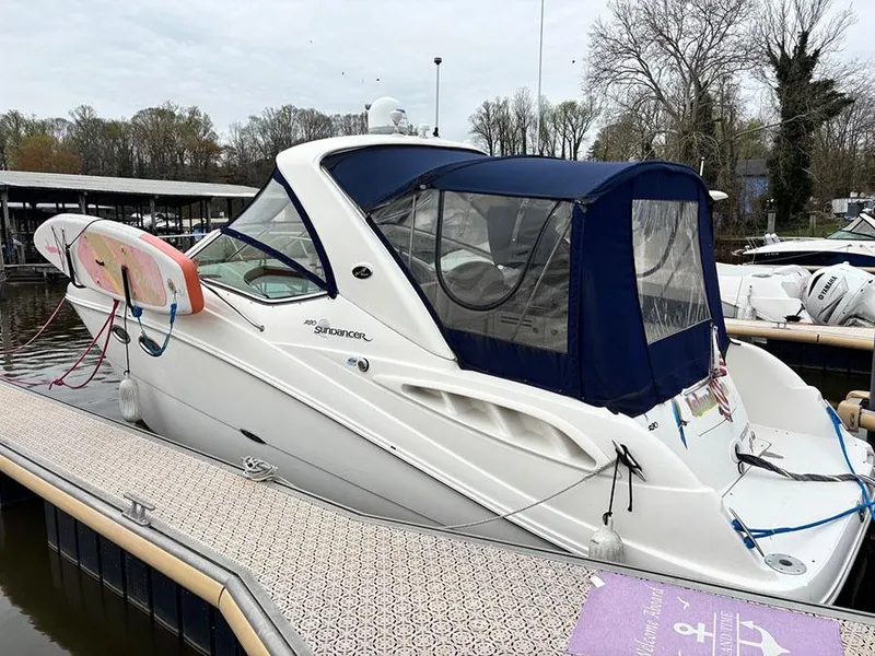Slide: The Image of 2006 Sea Ray 290 Sundancer docked, featuring a blue canopy and surfboards. - 2