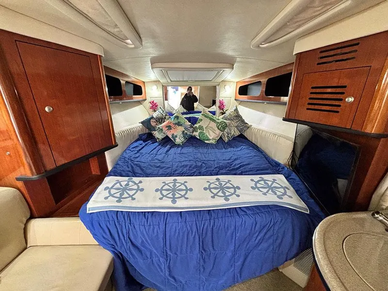 Slide: The Image of Interior of 2006 Sea Ray 290 Sundancer with blue bedding and wooden cabinets. - 21