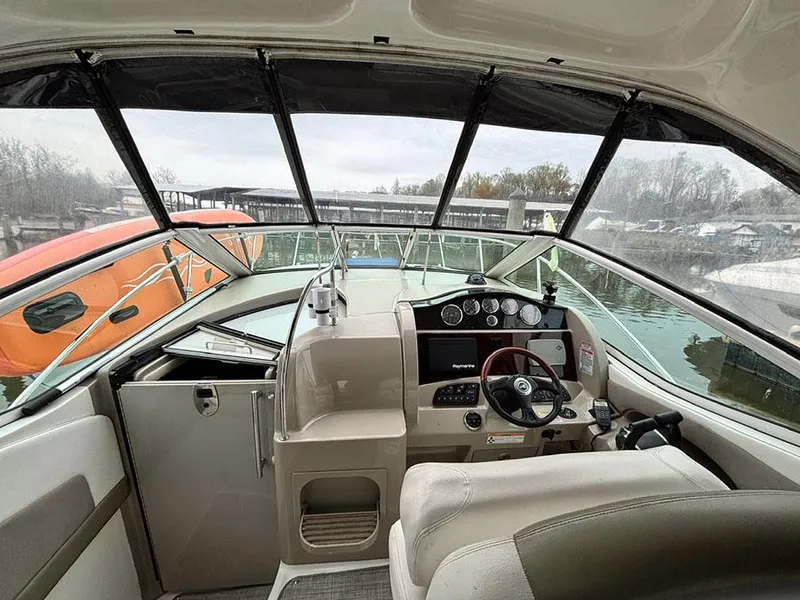 Slide: The Image of 2006 Sea Ray 290 Sundancer cockpit with steering wheel and dashboard, docked near water. - 9