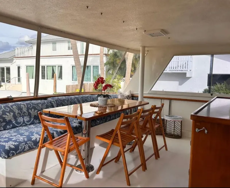 Slide: The Image of Interior of 1989 Hatteras 67 Cockpit Motor Yacht with dining area and wooden chairs. - 10