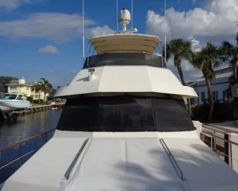 Slide: The Image of 1989 Hatteras 67 Cockpit Motor Yacht docked by palm trees under blue sky. - 43