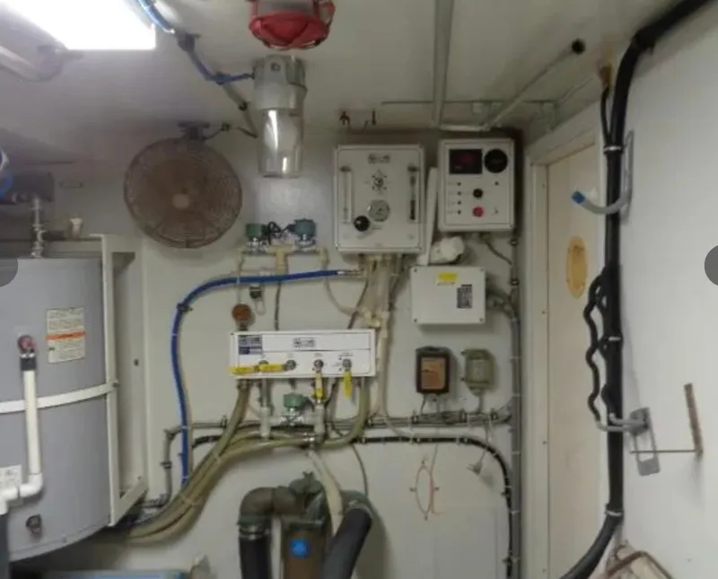 Slide: The Image of Engine room of 1989 Hatteras 67 Cockpit Motor Yacht with control panels and piping. - 29