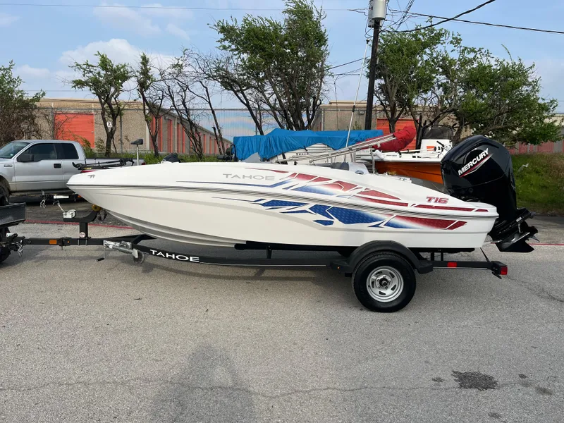 Slide: The Image of 2022 Tahoe T16 boat on trailer, parked outdoors, featuring vibrant red and blue graphics. - 18