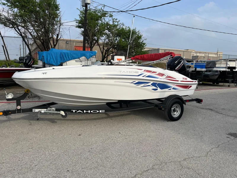 Slide: The Image of 2022 Tahoe T16 boat on trailer, parked outdoors with colorful graphics. - 19