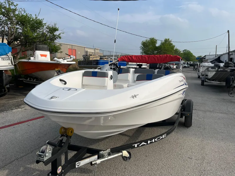 Slide: The Image of 2022 Tahoe T16 boat on trailer, parked outdoors with other boats. - 2