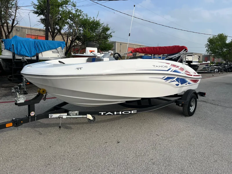 Slide: The Image of 2022 Tahoe T16 boat on trailer, white with blue and red accents, parked outdoors. - 20