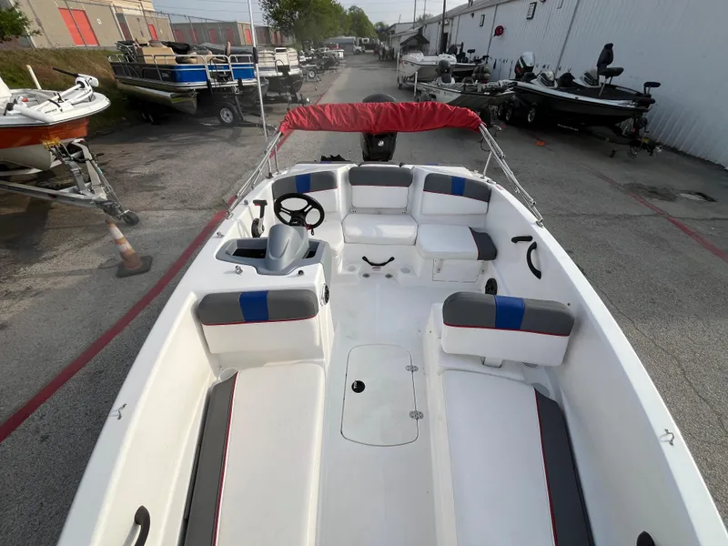 Slide: The Image of 2022 Tahoe T16 boat with red canopy and seating, parked outdoors. - 27