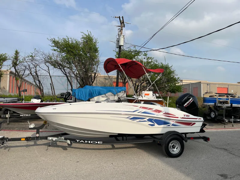 Slide: The Image of 2022 Tahoe T16 boat with red canopy on trailer, parked outdoors. - 38