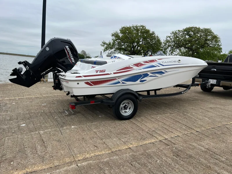 Slide: The Image of 2022 Tahoe T16 boat on trailer, parked near a lake with trees in the background. - 42