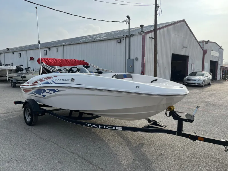Slide: The Image of 2022 Tahoe T16 boat on trailer, parked outside a warehouse. - 6