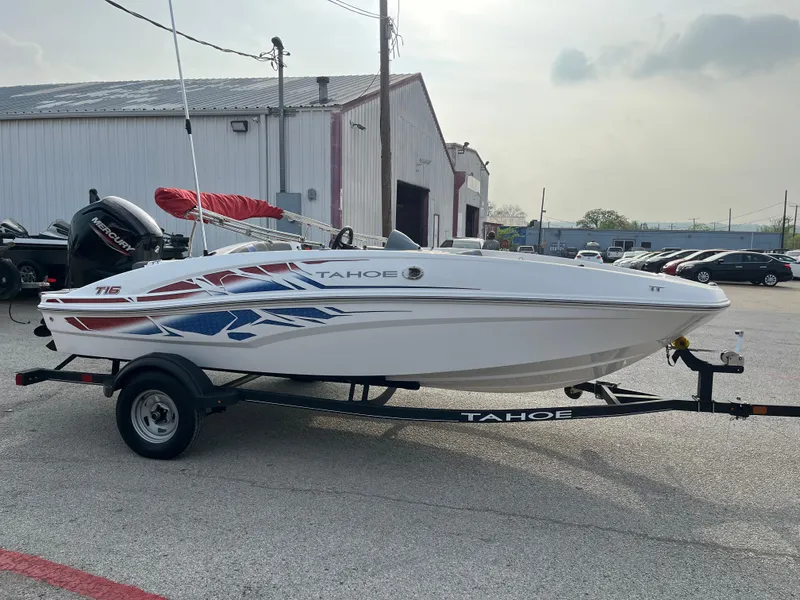 Slide: The Image of 2022 Tahoe T16 boat on trailer, parked outdoors near industrial building. - 7