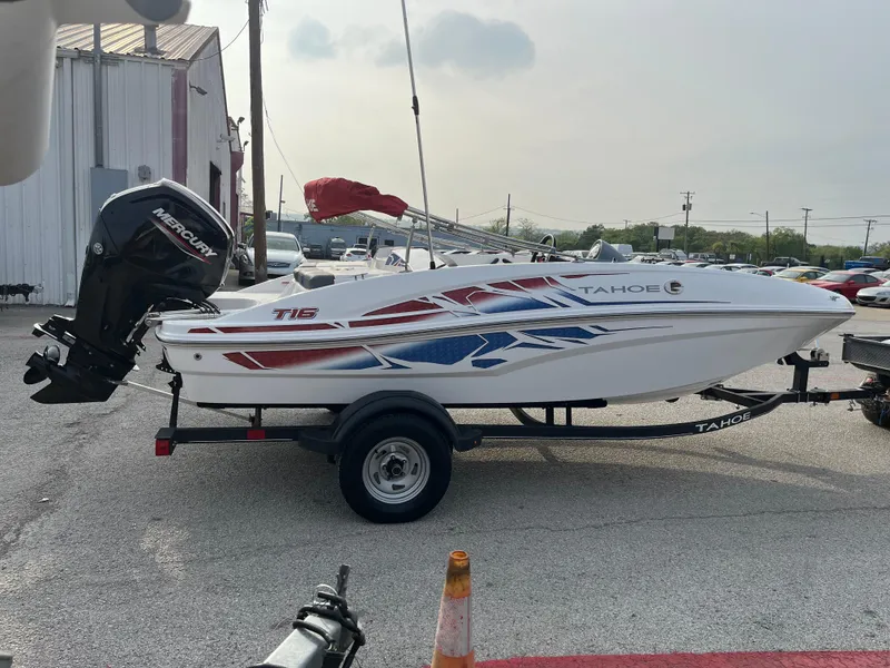Slide: The Image of 2022 Tahoe T16 boat on trailer with vibrant red and blue graphics, parked outdoors. - 8