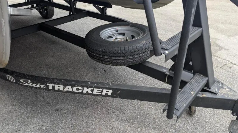 Slide: The Image of 2024 Sun Tracker Bass Buggy 18 DLX trailer with spare tire on asphalt. - 5