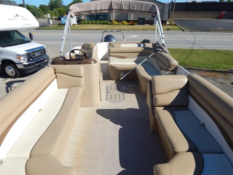 Slide: The Image of 2016 Bennington 24 SSLX pontoon boat with beige seating and canopy, parked near a road. - 12